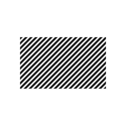 Black and white striped outdoor rug shown on decking beside patio furniture