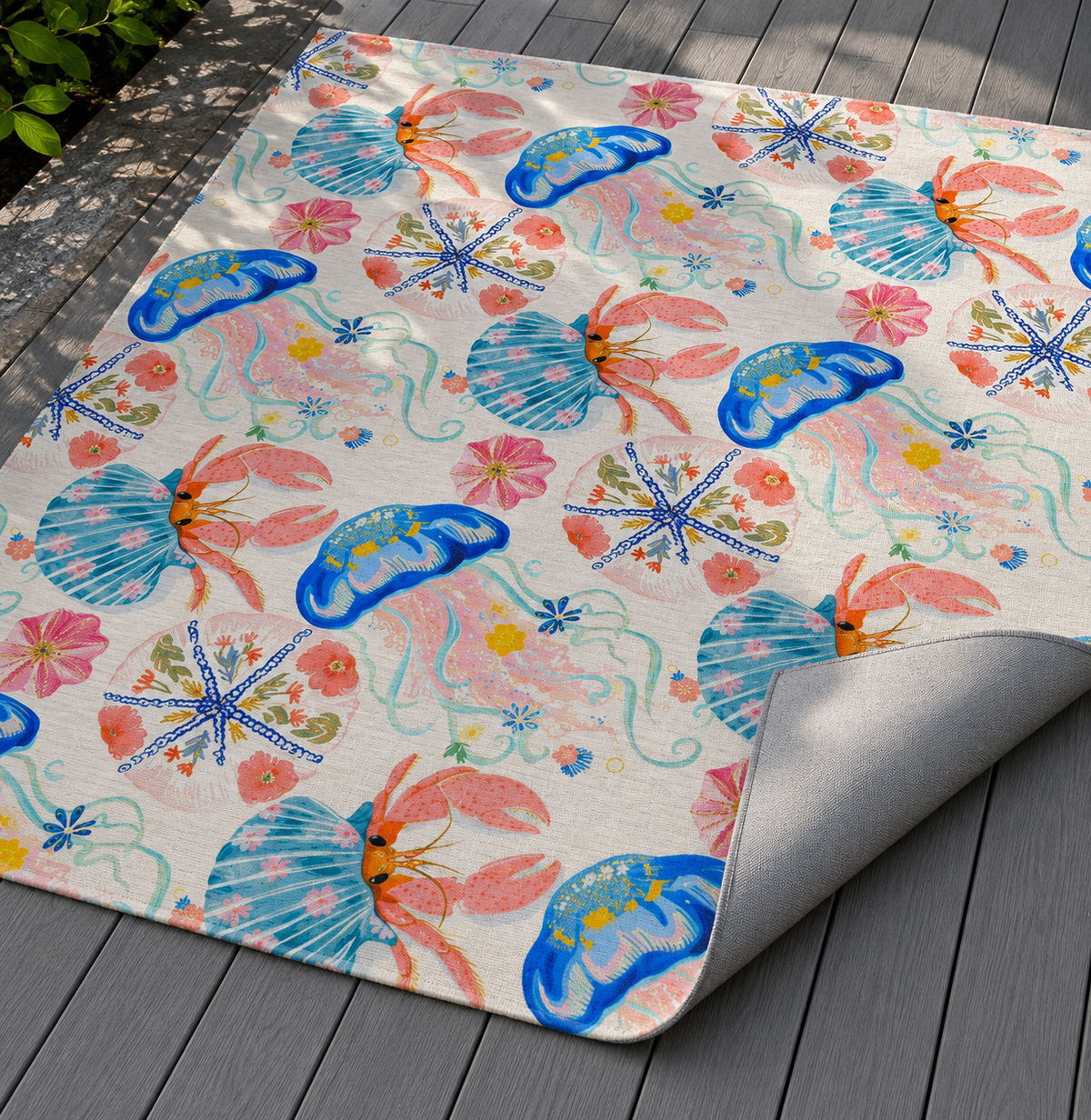Coastal seashell outdoor rug with the corner folded back — matte grey non-slip backing