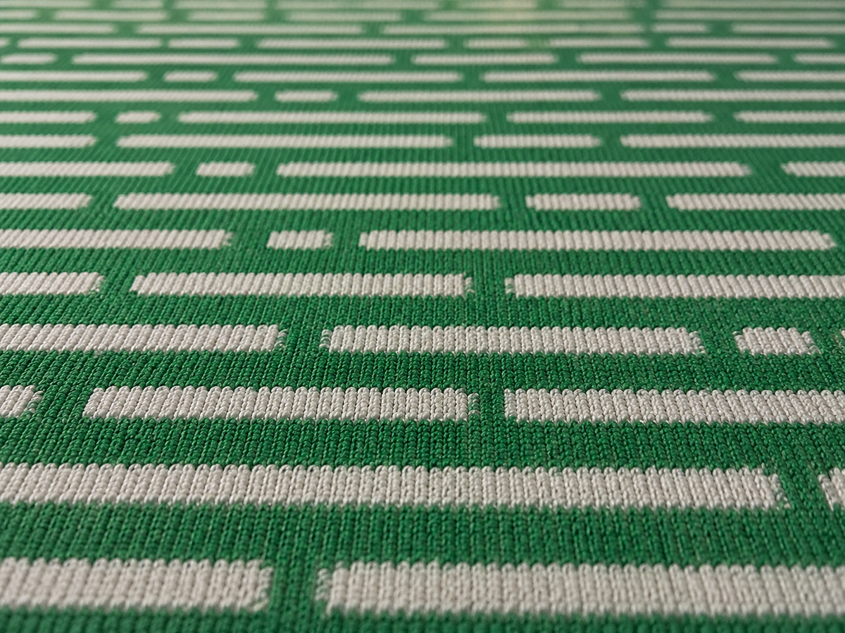 Close-up of the green basketweave outdoor rug — short, dense low-pile chenille nap