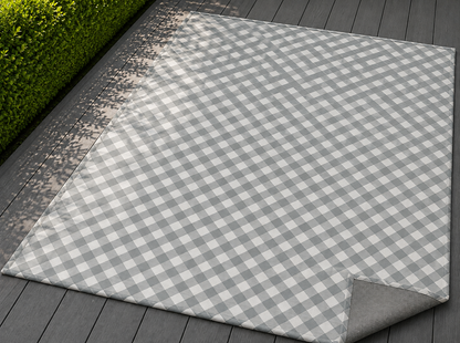 Grey diagonal gingham outdoor rug with the corner folded back — matte grey non-slip backing