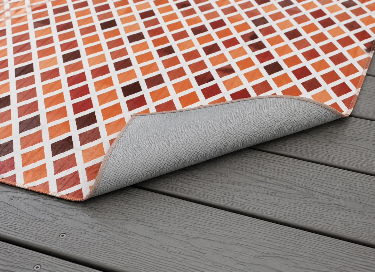 Rust harlequin diamond outdoor rug with the corner folded back — matte grey non-slip backing