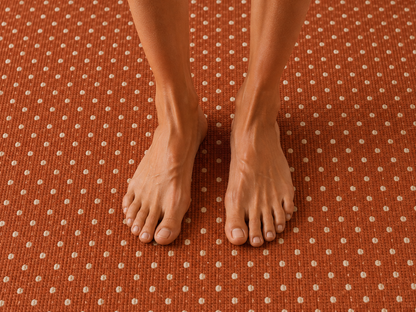 Bare feet standing on the terracotta pin dot outdoor rug — soft low-pile chenille