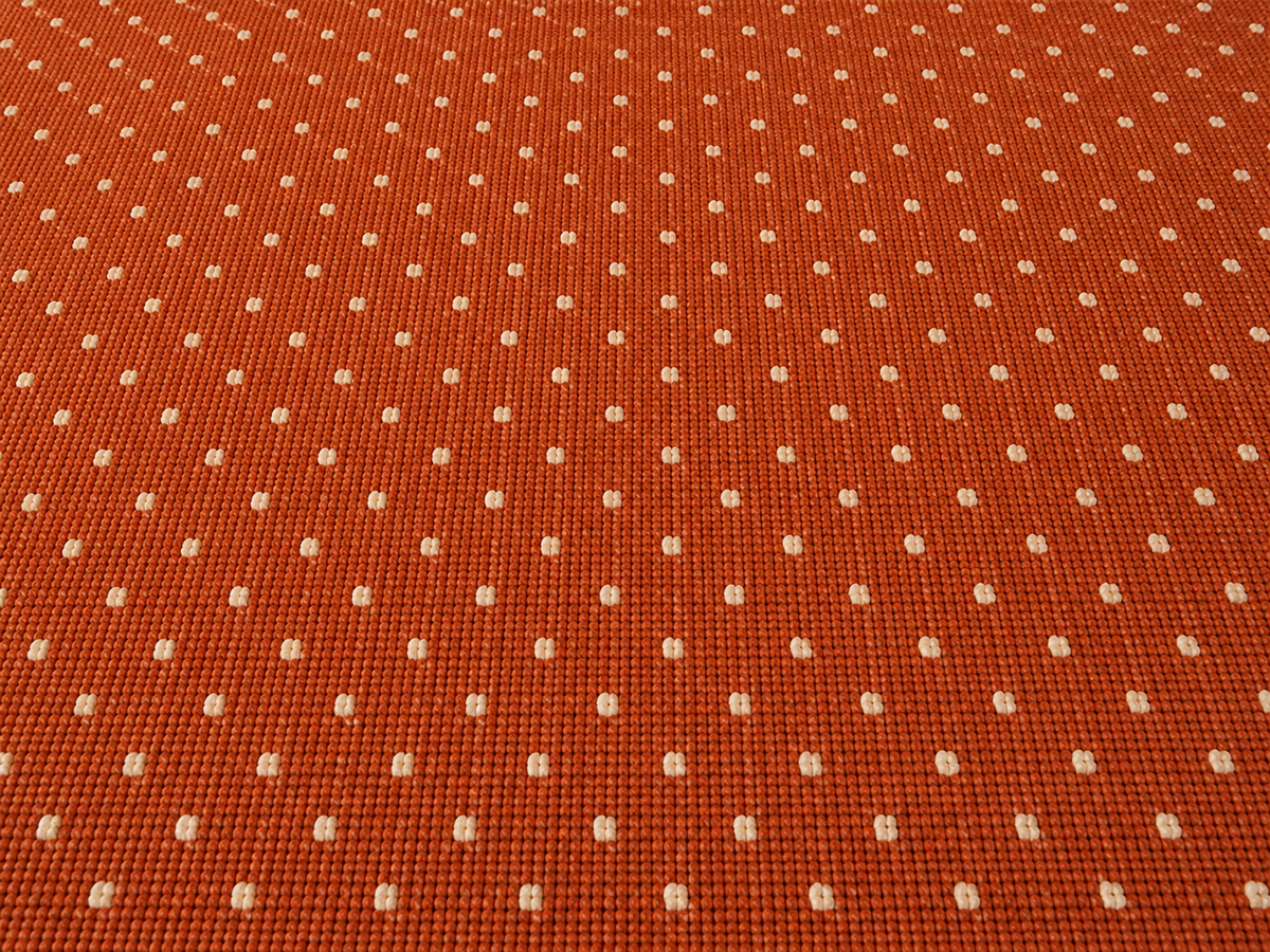 Close-up of the terracotta pin dot outdoor rug — short, dense low-pile chenille nap