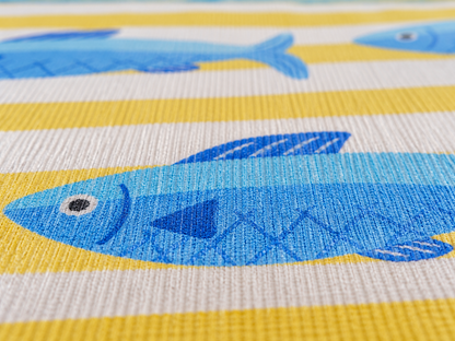 Close-up of the yellow stripe and blue fish outdoor rug — short, dense low-pile chenille nap